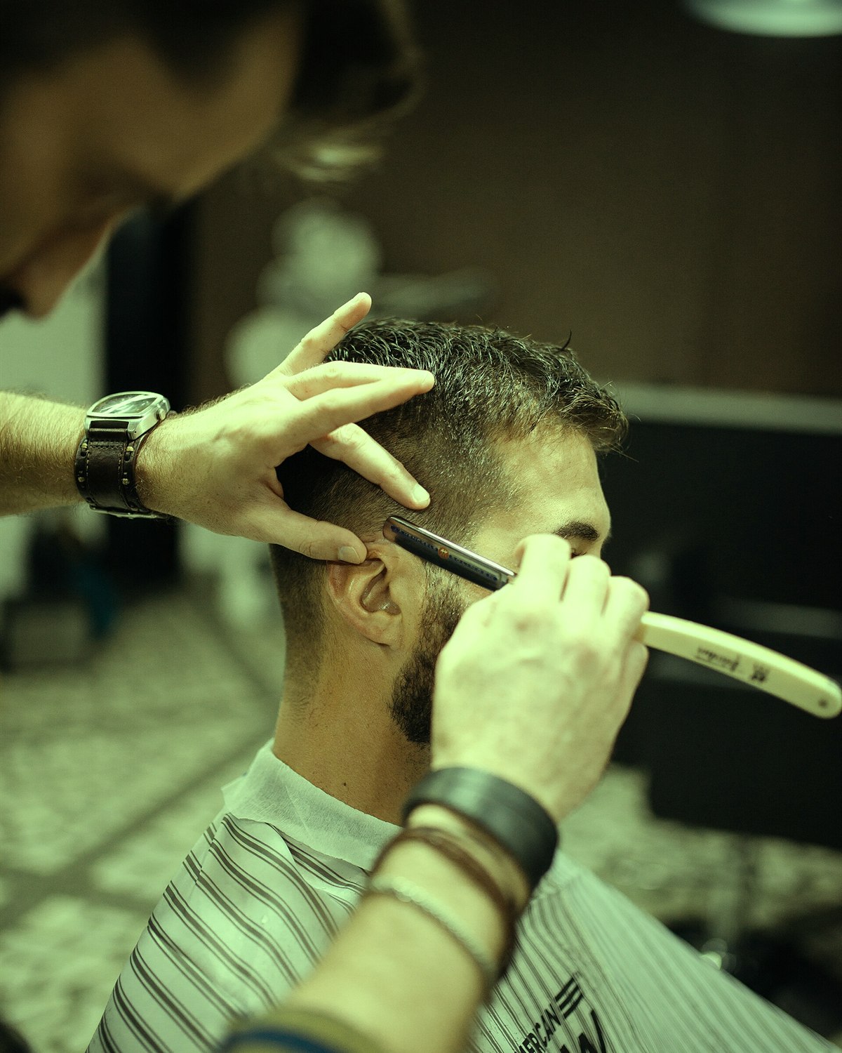 Barbeiro a finalizar um corte de cabelo com tesoura e pente